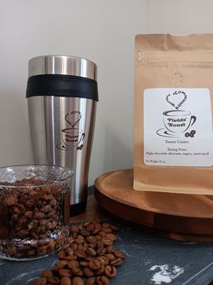 display of a glass of coffee beans next to the bag and a tumbler